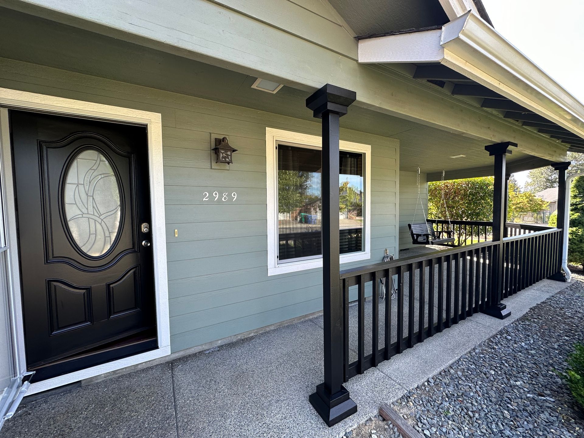 The front of a house with a porch and a black door.