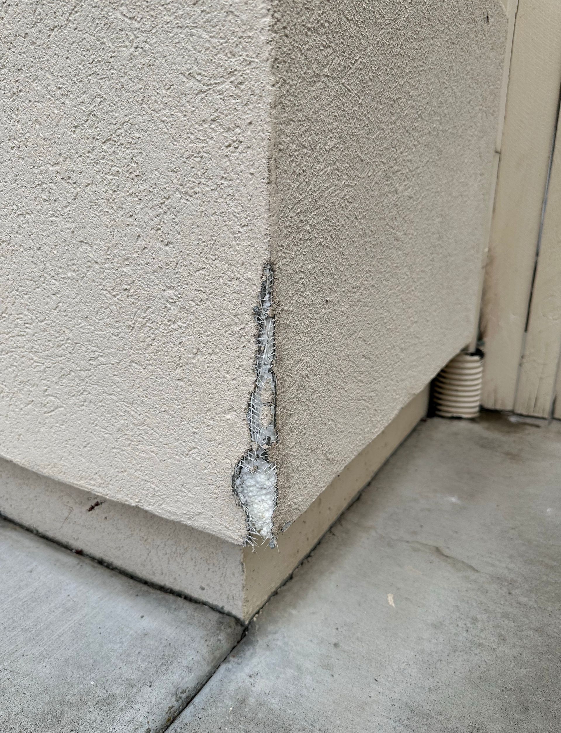 A close up of a corner of a building with a hole in it.