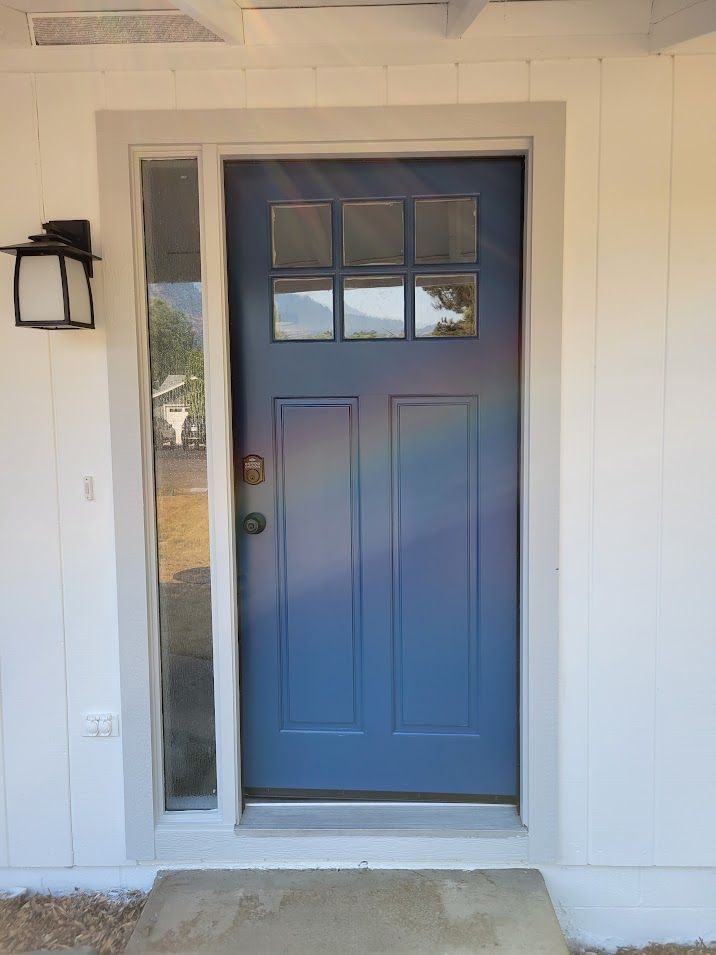 A blue front door with a white trim and a window on a white house.