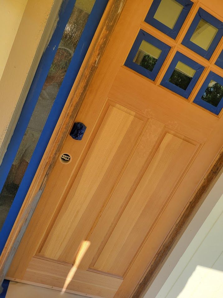 A wooden door with blue trim is being painted.