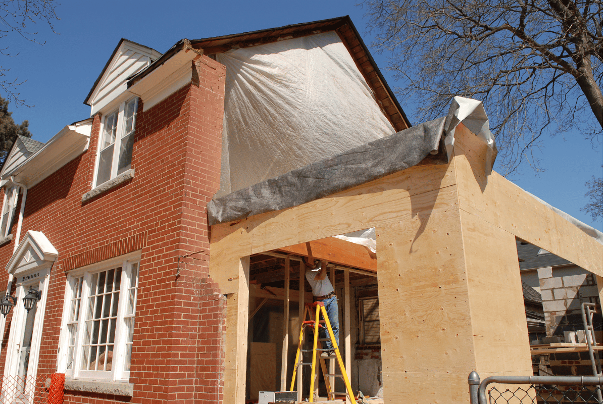 A brick house is being remodeled with a wooden extension