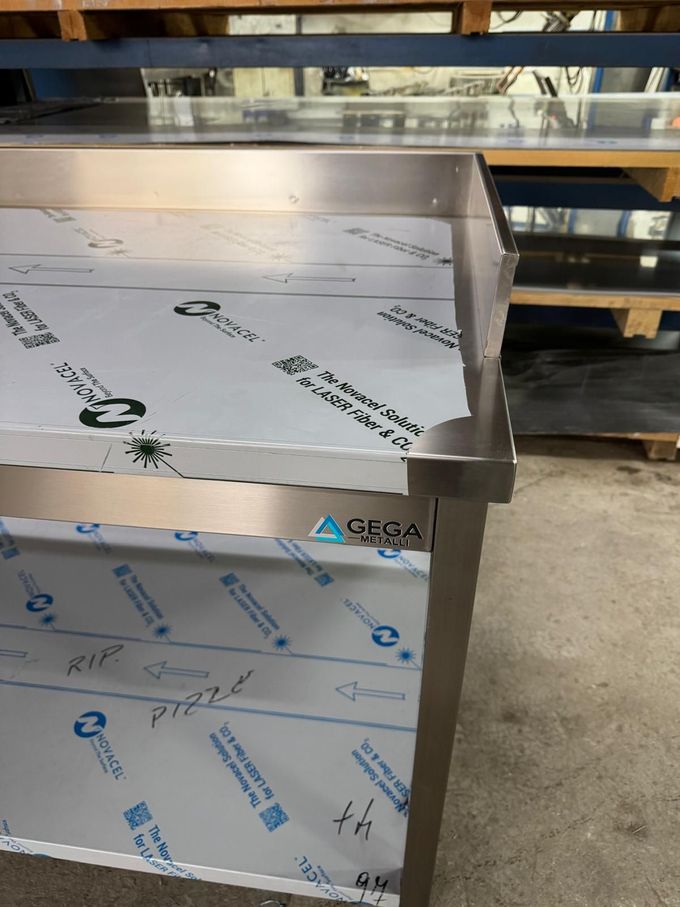 Tavoli da lavoro e armadietti in acciaio inox per cucine professionali in un'area adibita a officina/magazzino.