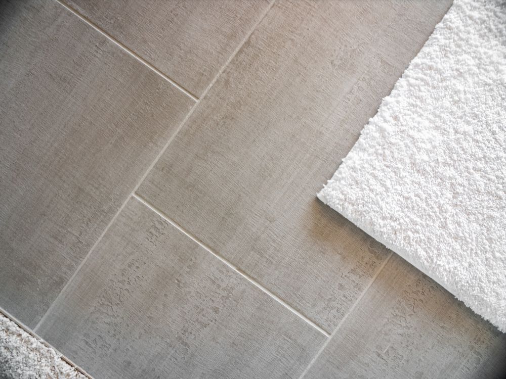 Tan tiled floor with white towel, angled view.