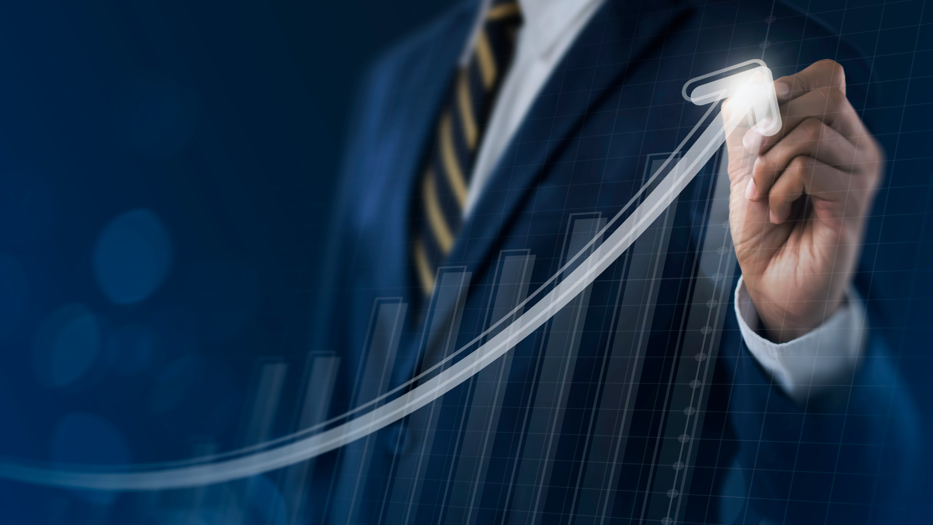 A man in a suit and tie is drawing a graph with a marker.