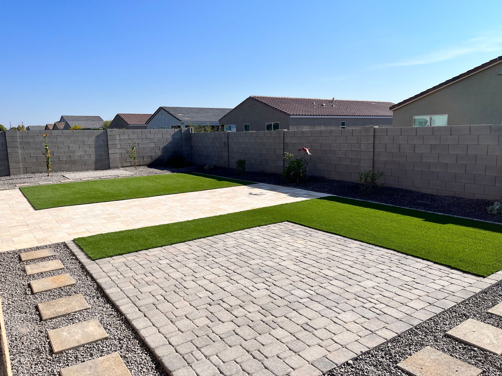 A backyard with a brick fence and a lush green lawn.