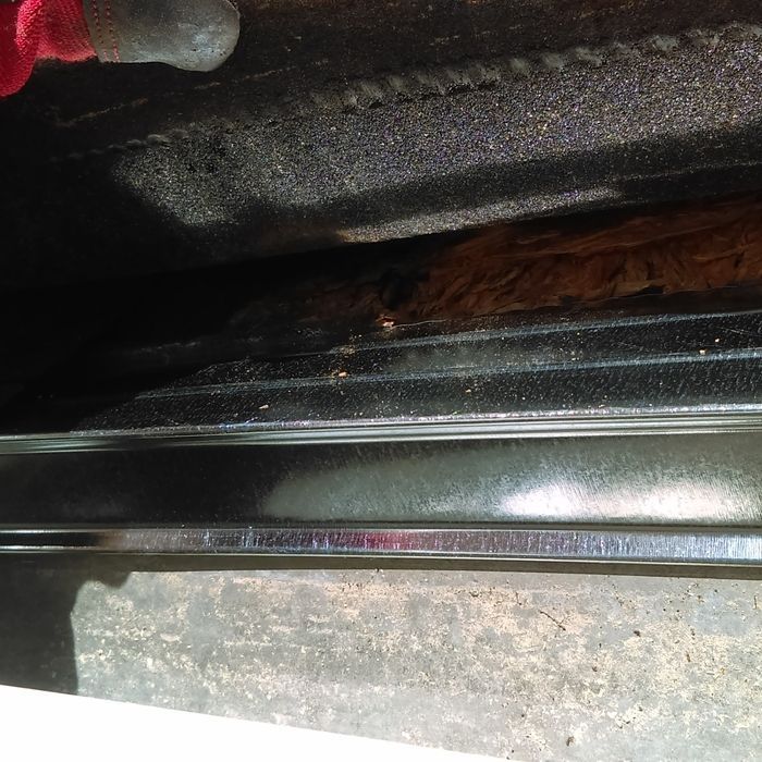 Close-up view of a dark oven interior with metal racks and a brown, fibrous substance.