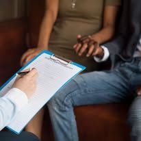 Person holding clipboard; couple holding hands, sitting together.