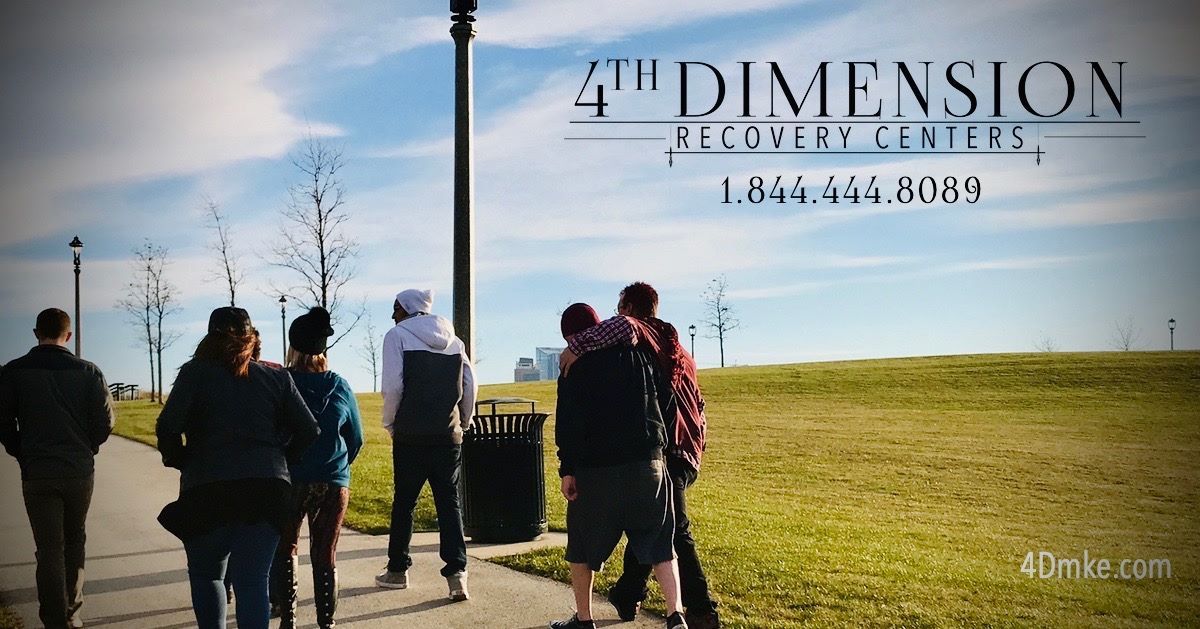 Group walking on a path in a park with a telephone number and a recovery center's logo.