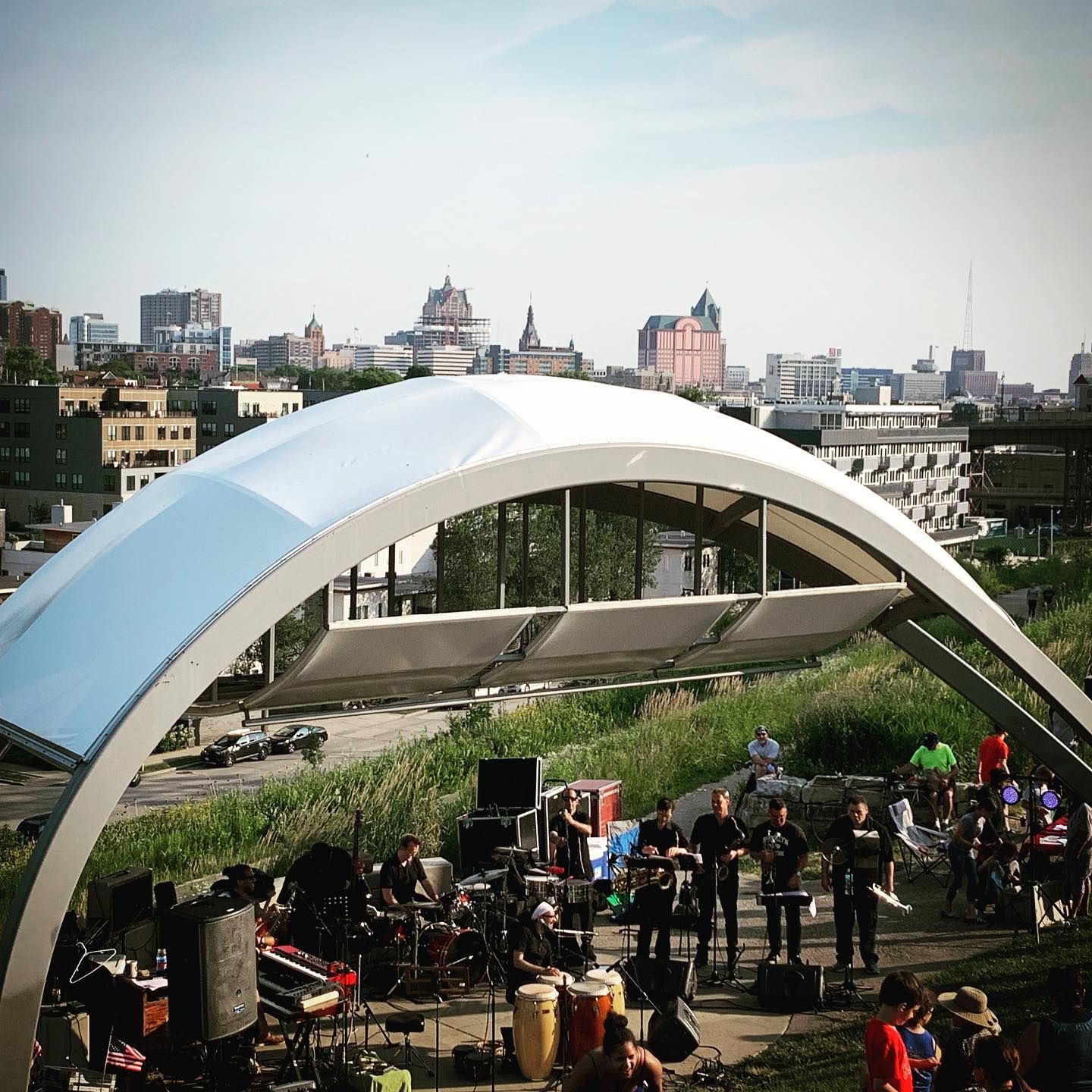 Band performing under a white canopy overlooking a city skyline.