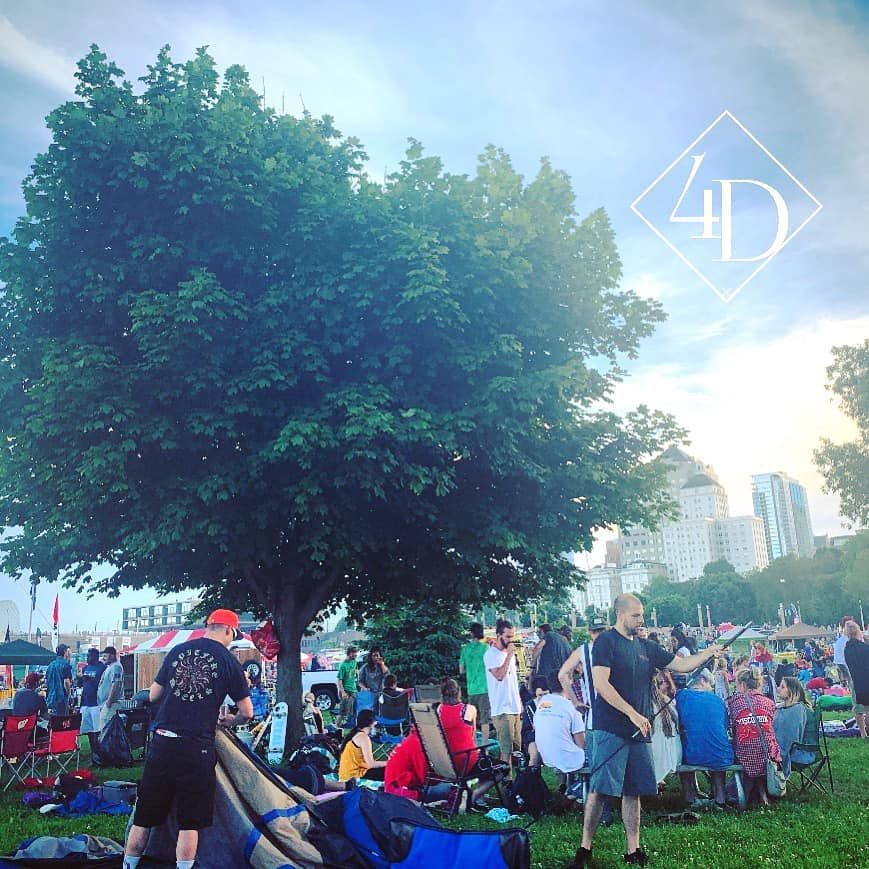 People gathered in a park under a large tree, possibly for an outdoor event.