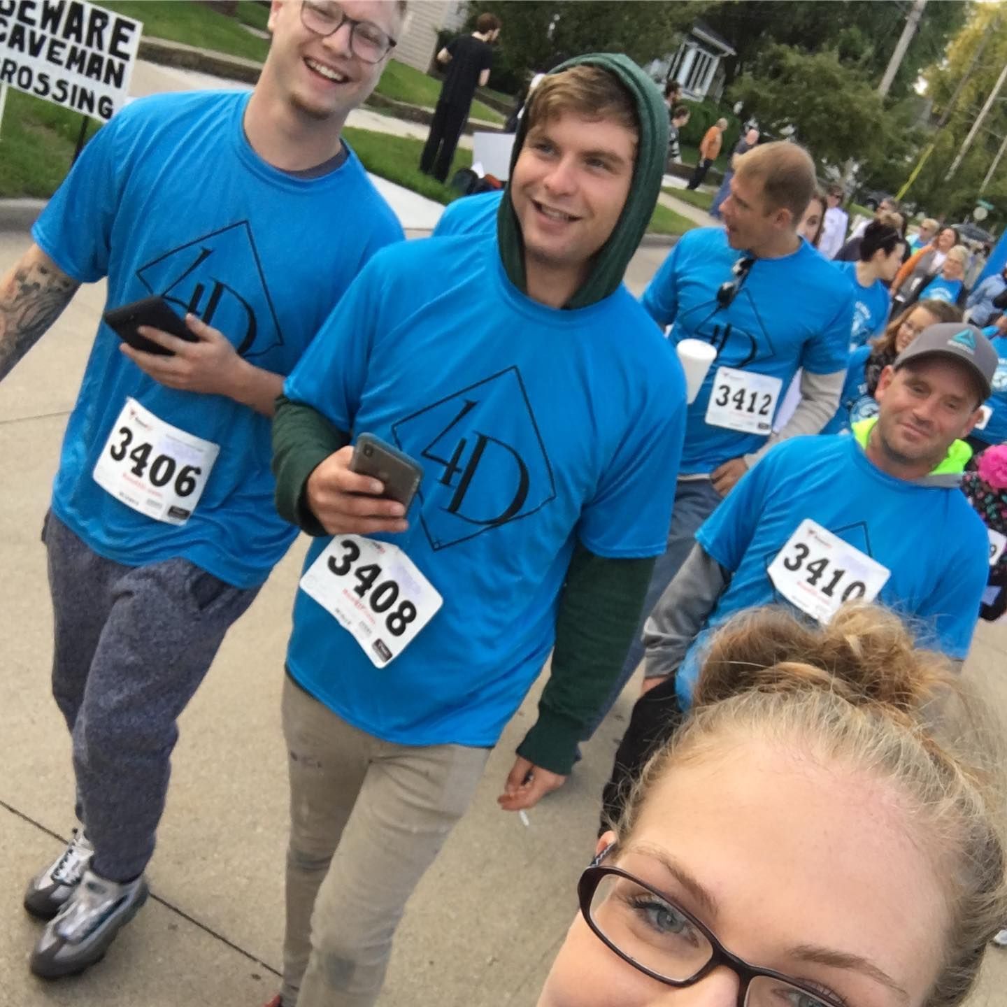 Group of people in blue shirts with race numbers, smiling at the camera.