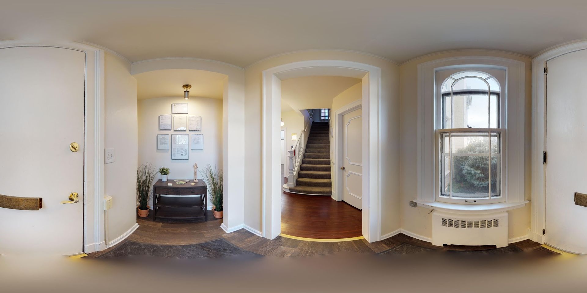 Interior view of a hallway with arched doorways, leading to a staircase and a room with a piano.