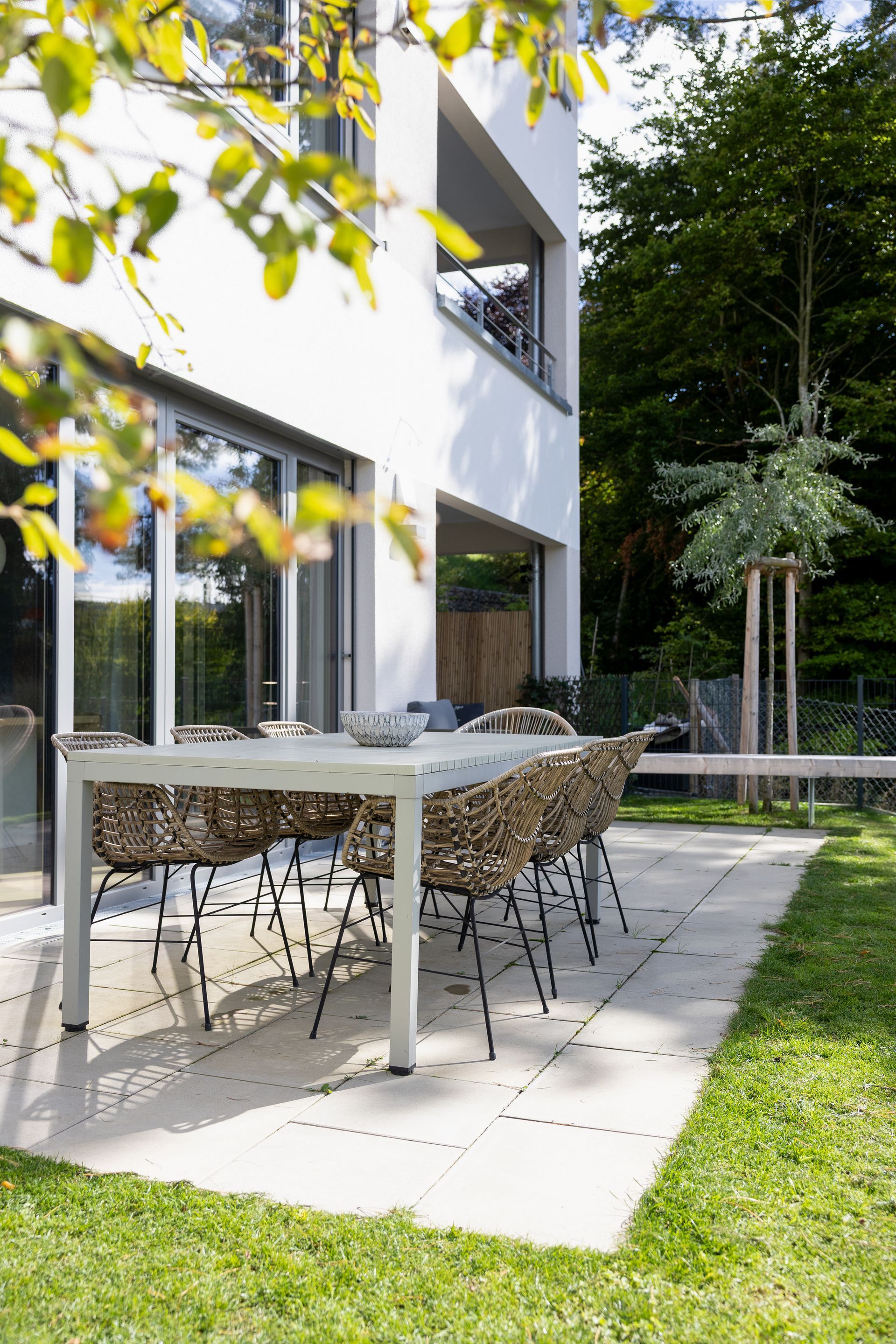 Terrasse mit Tisch und Korbstühlen auf einer Steinterrasse, umgeben von Grün.Fotograf Tübingen. Fotograf Reutlingen.