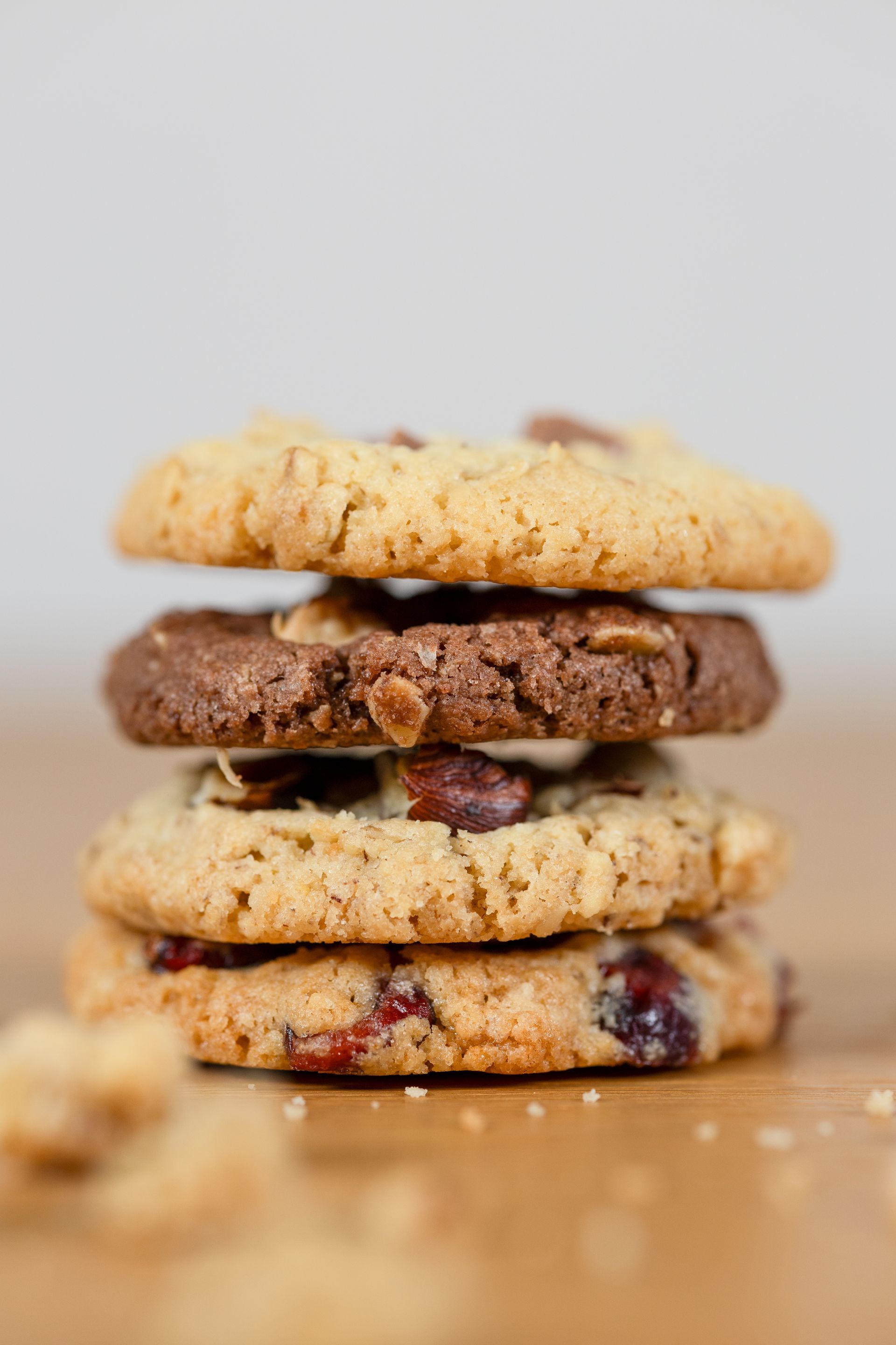 Ein Stapel aus vier verschiedenen Keksen auf einer Holzoberfläche, Krümel sichtbar.Fotograf Tübingen. Fotograf Reutlingen.