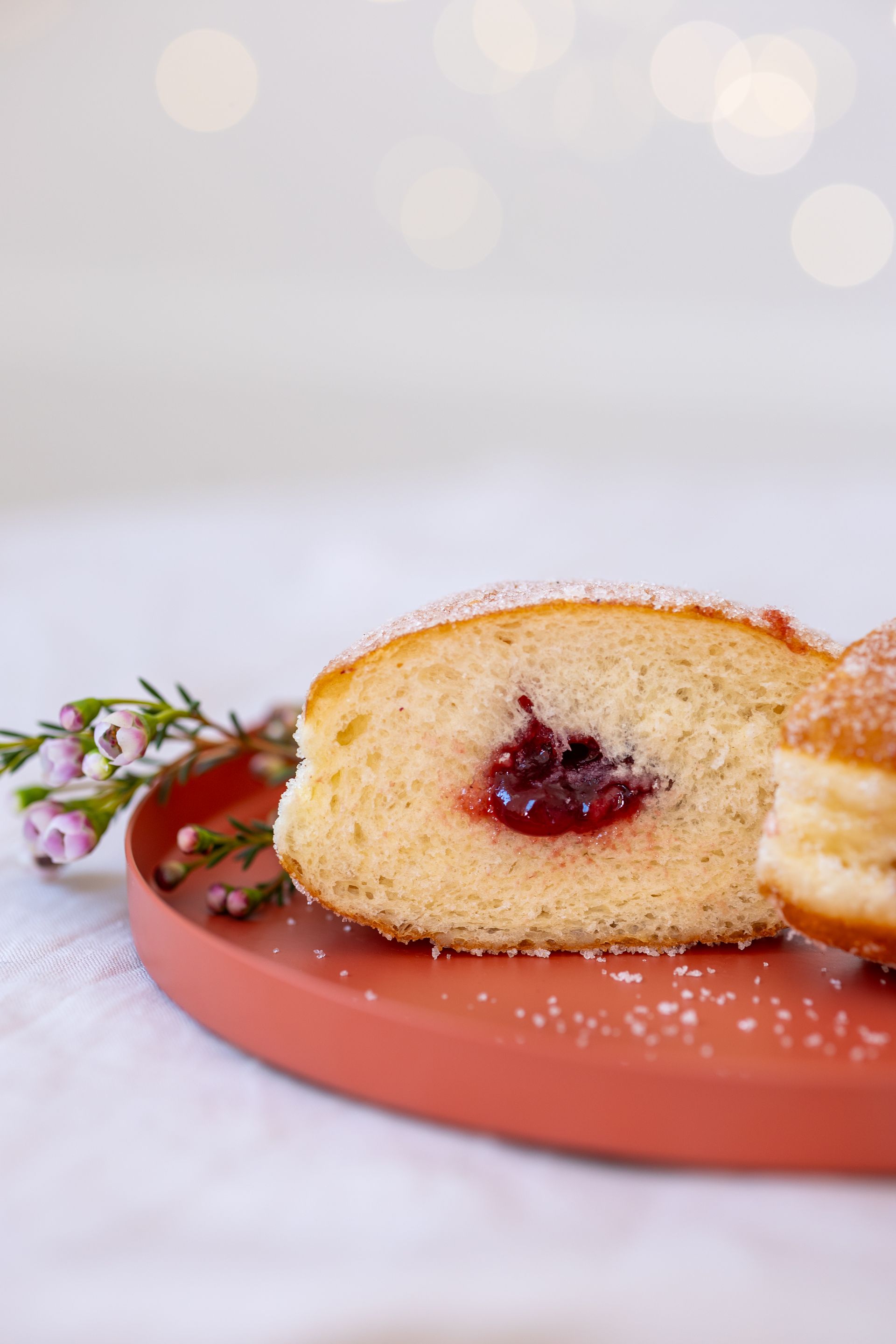 Berliner mit Himbeerfüllung auf einem orangefarbenen Teller, mit Zucker bestreut. .Fotograf Tübingen. Fotograf Reutlingen.