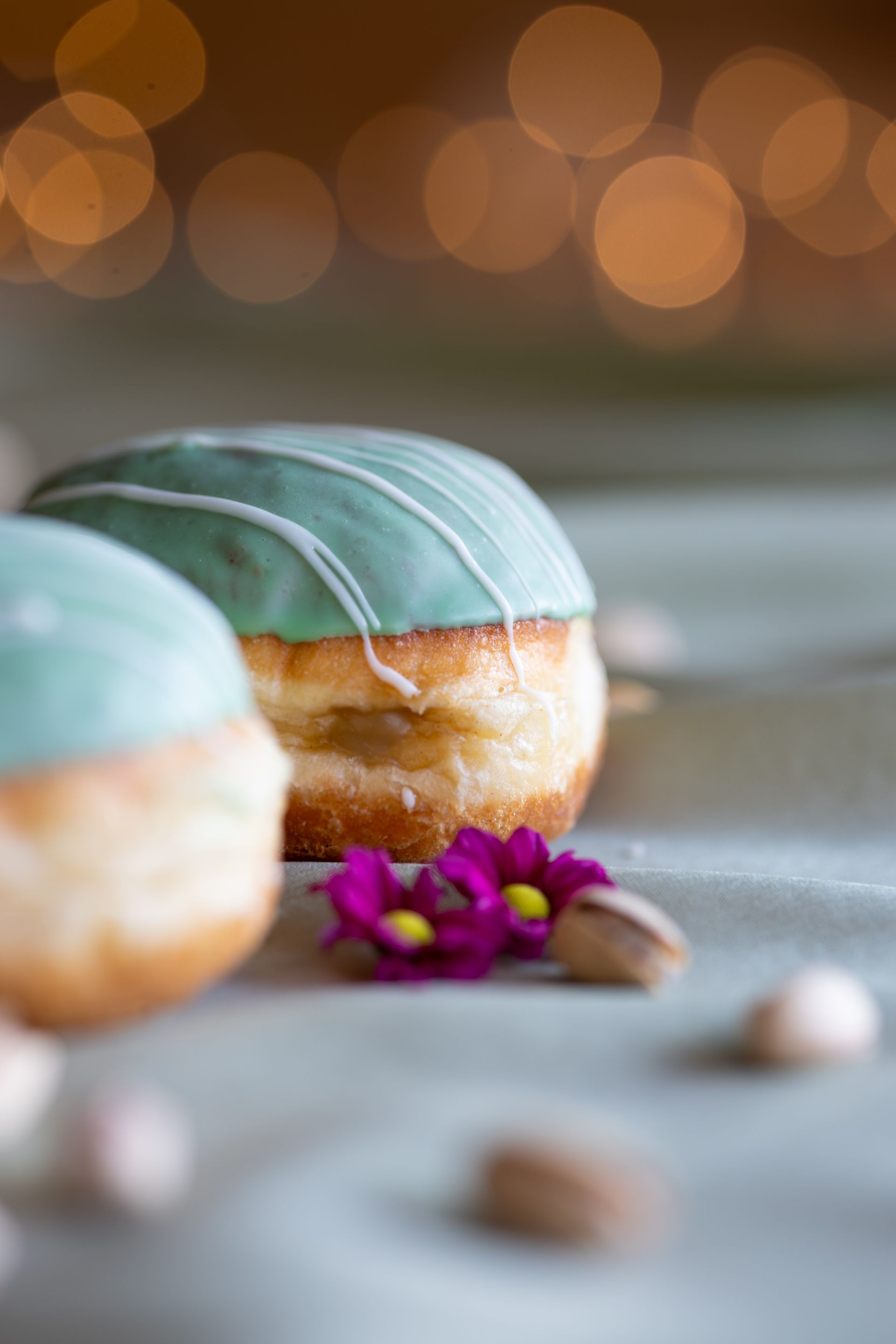 Zwei Berliner mit grünem Zuckerguss und weißem Zuckerguss, Pistazien.Fotograf Tübingen. Fotograf Reutlingen.