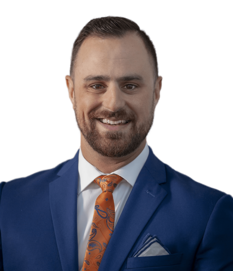 A man in a blue suit and orange tie is smiling.