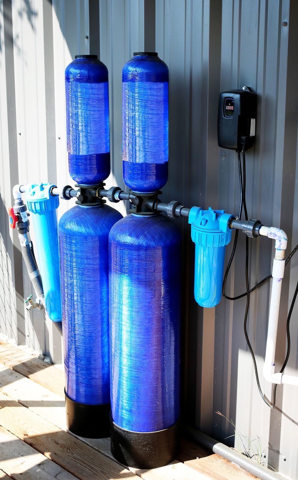 Two blue water filters are sitting next to each other on the side of a building.