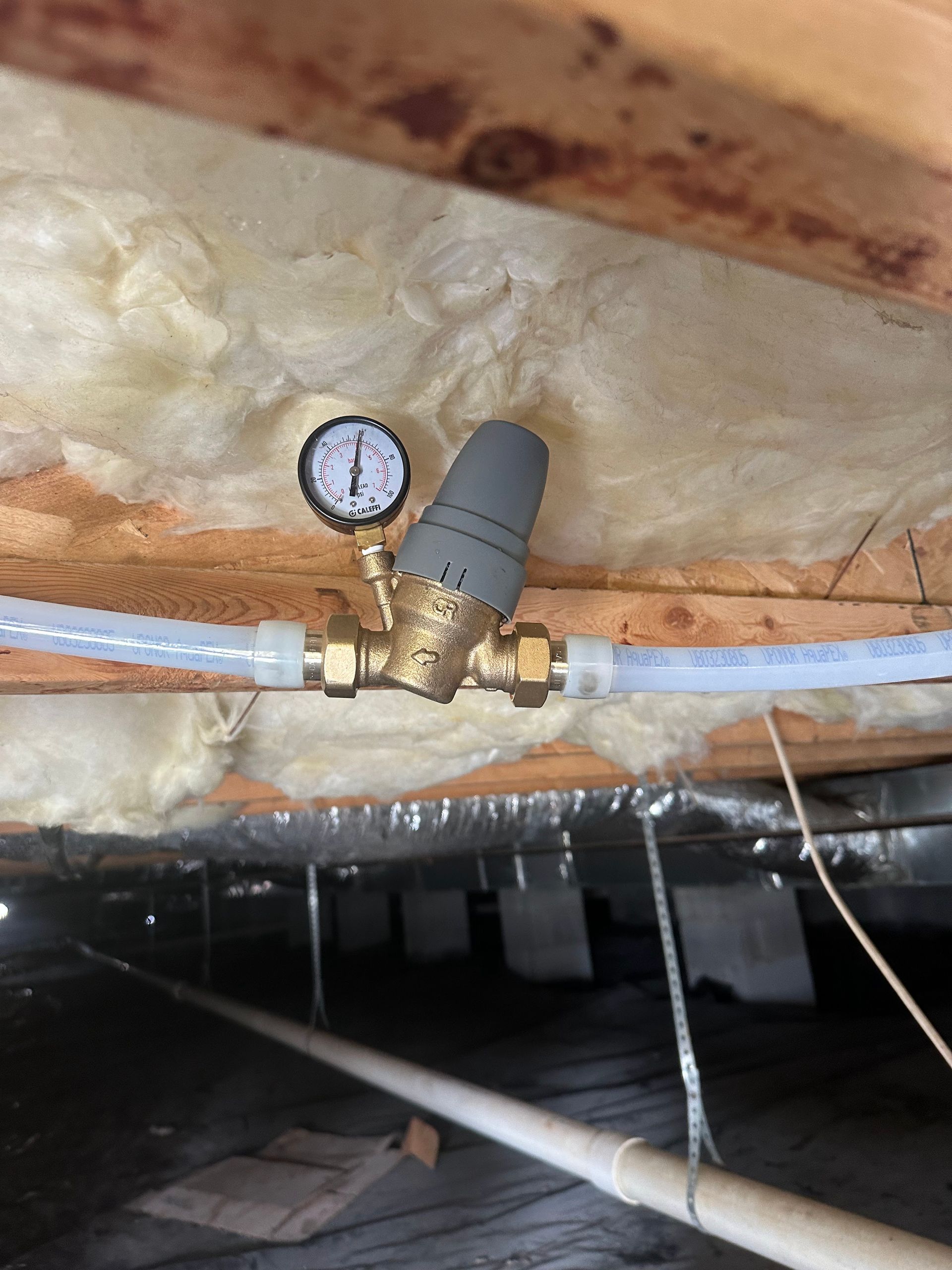 Water pressure regulator with gauge in a crawl space.