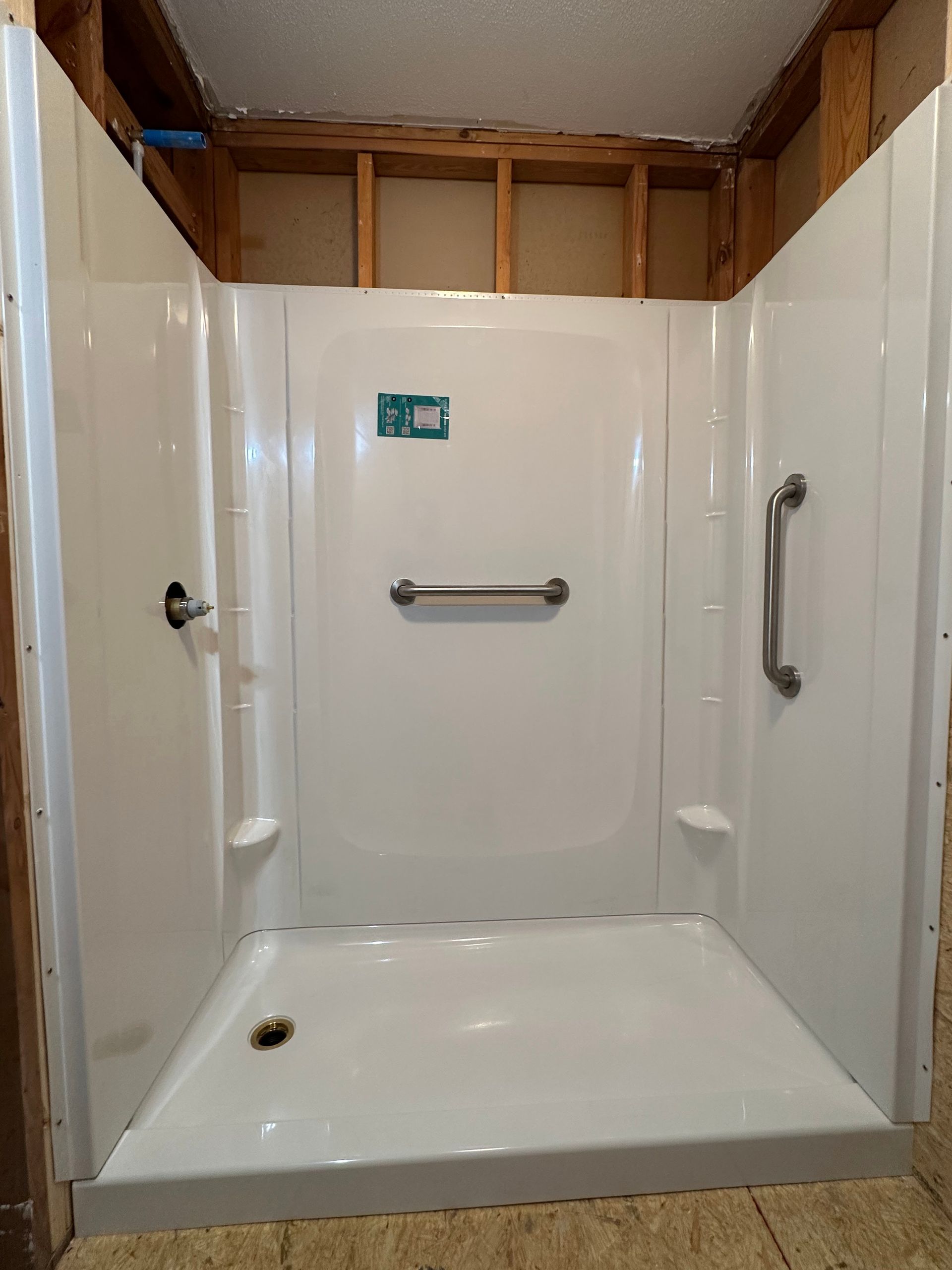 White accessible shower stall with grab bars, ready for installation.
