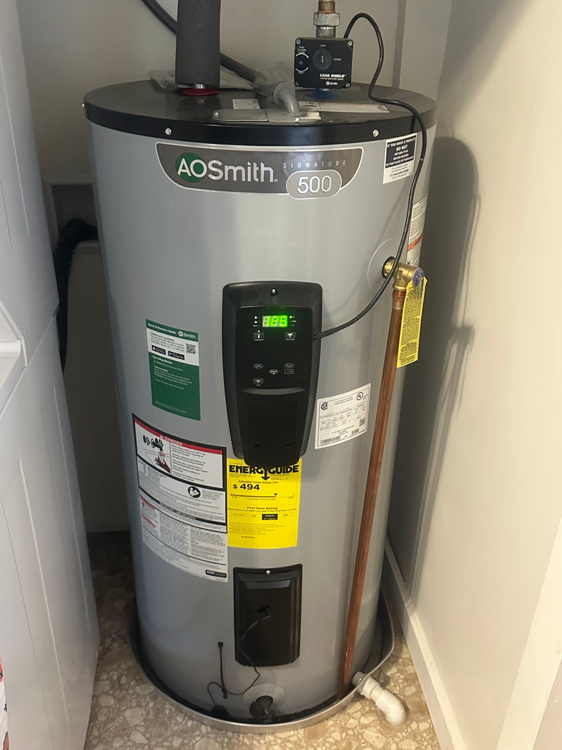 A. O. Smith electric water heater in a utility closet; the unit is gray with a black control panel.
