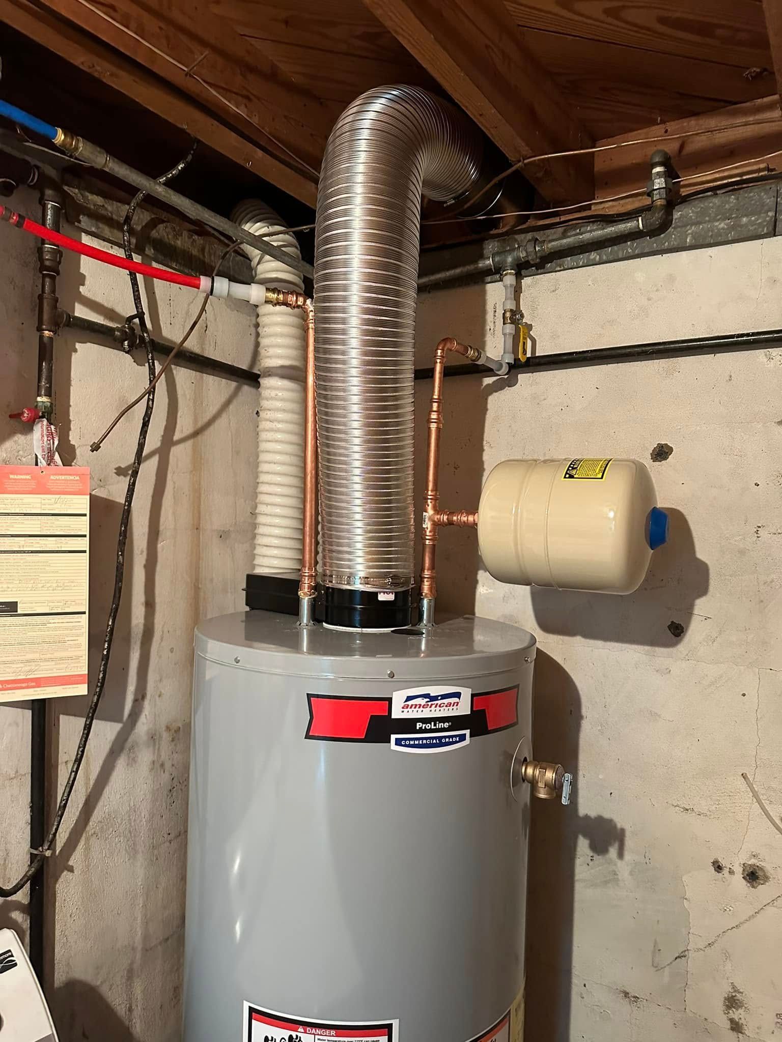 Water heater in a basement. Silver tank with vent pipe, connected to plumbing and an expansion tank.