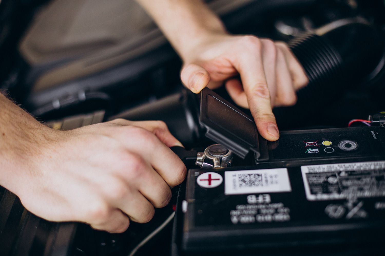 A person is plugging a charger into a car battery.