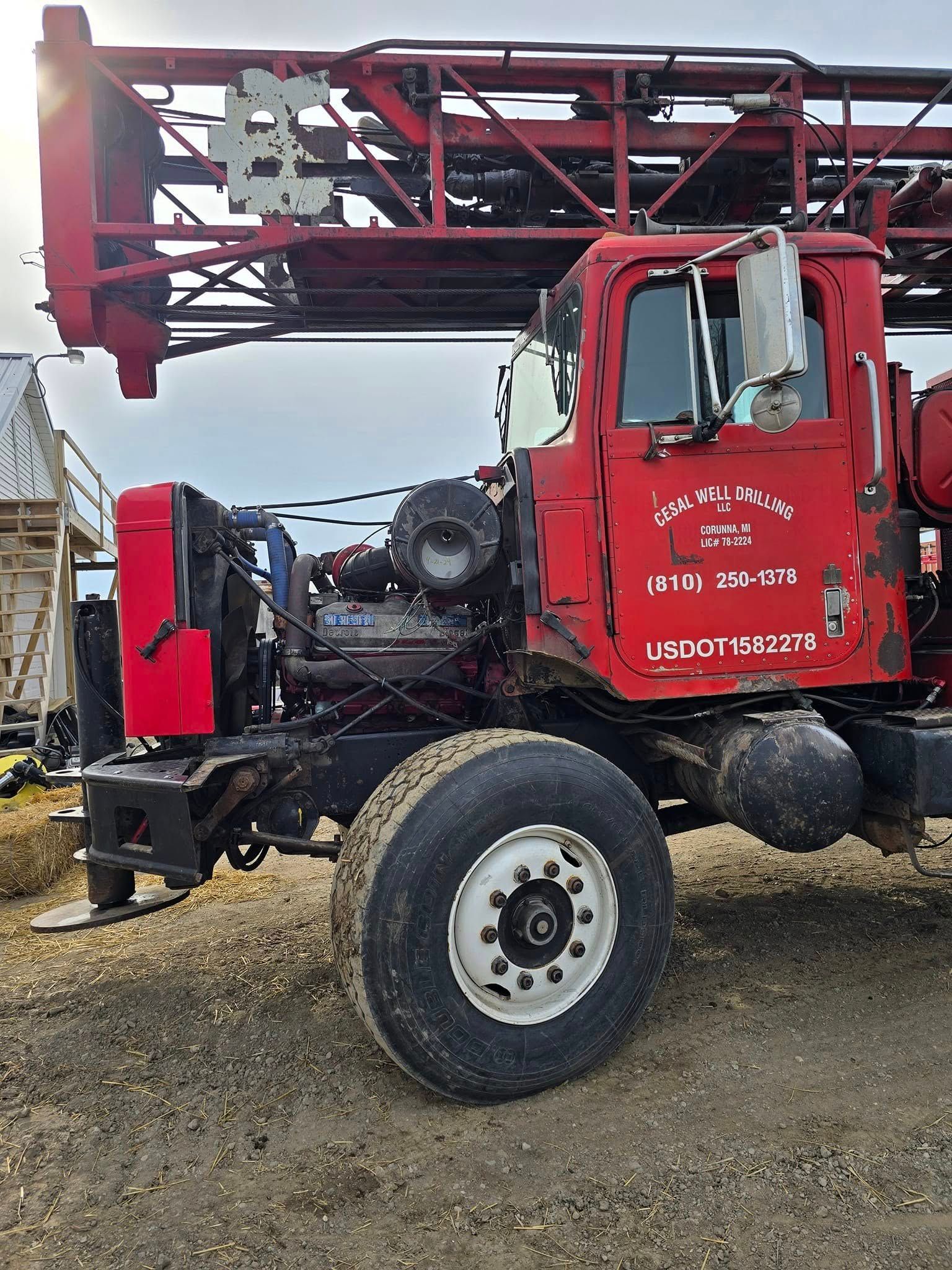 A red truck is parked in a dirt field.