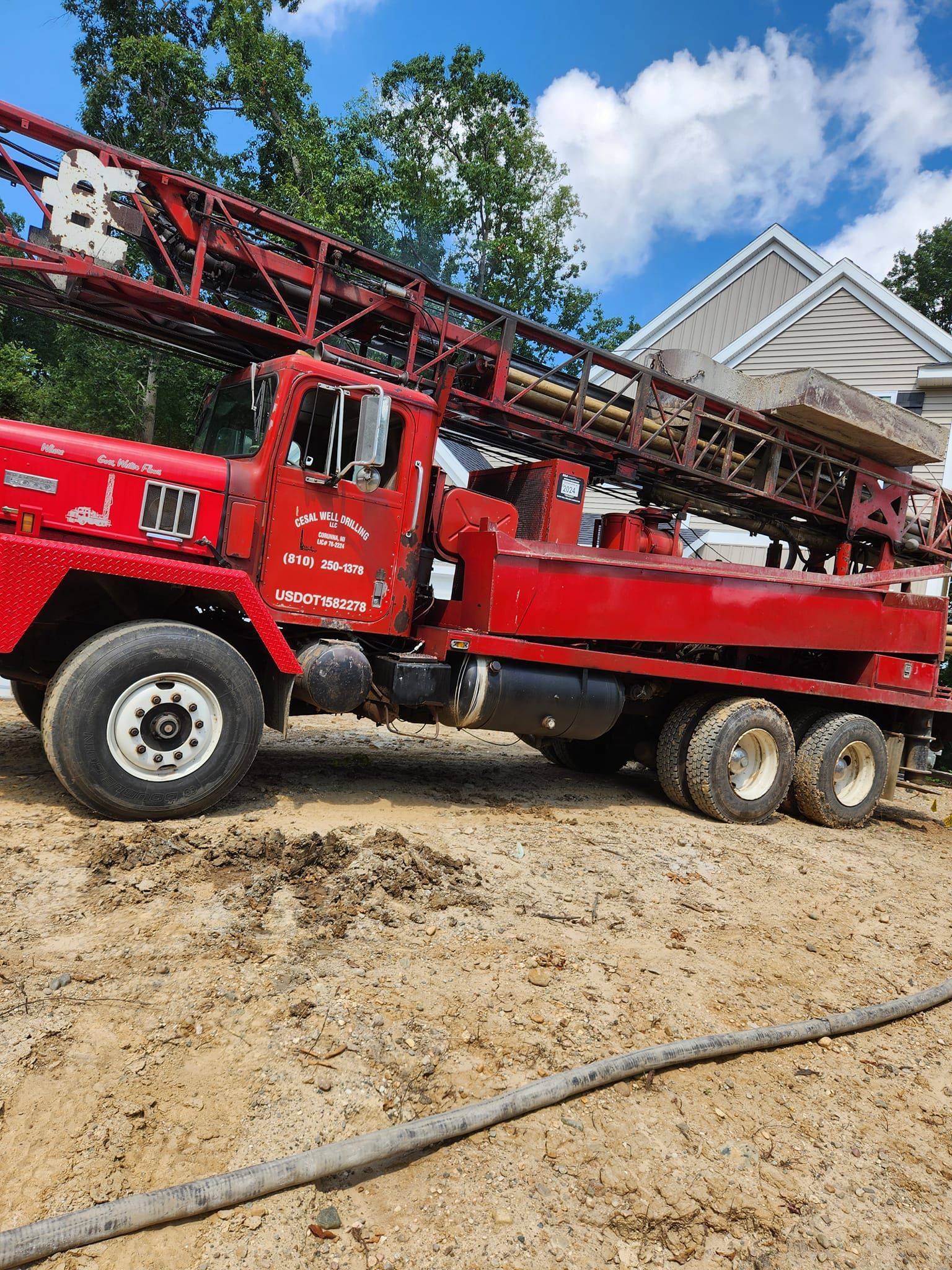 A man is standing in the dirt next to a red truck.