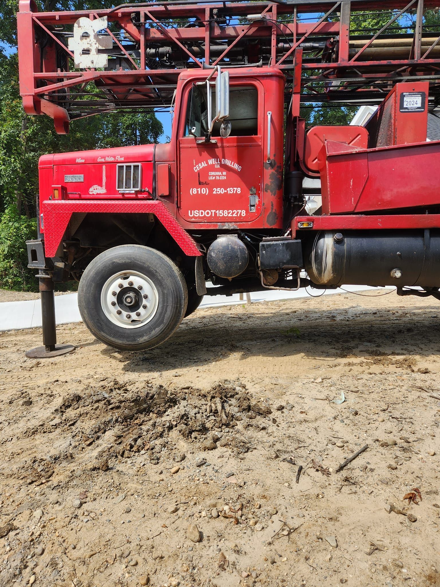 A red truck is parked in a dirt field.
