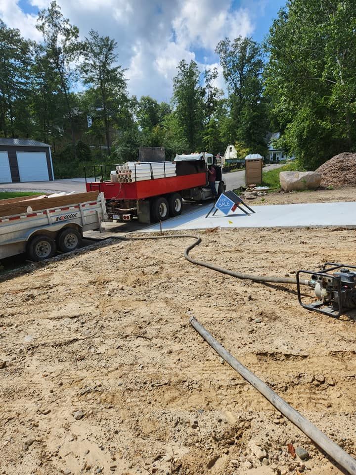 A red truck is parked on a dirt road next to a trailer.