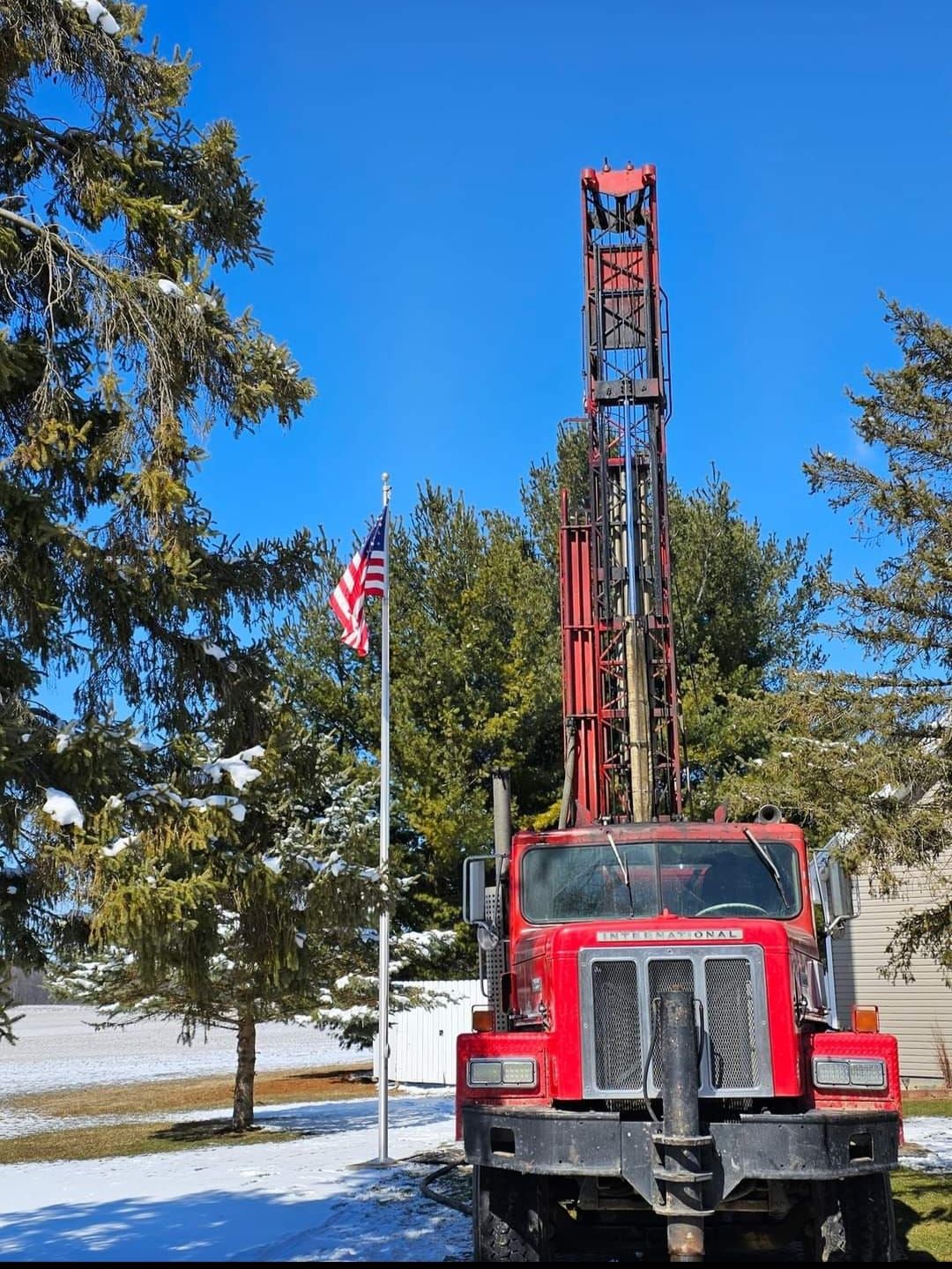 A red truck is parked in front of an american flag