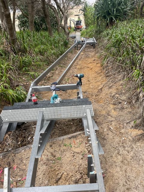 A ladder is sitting in the middle of a dirt path.