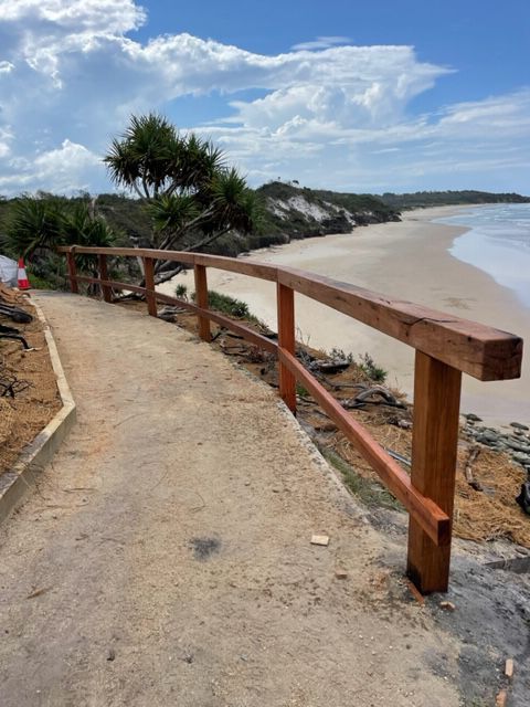 A wooden walkway leading to a beach with a wooden railing