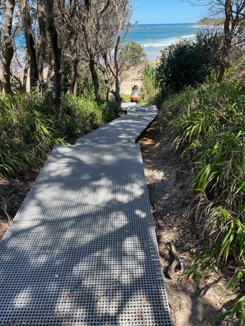 A wooden walkway leading to the beach in the woods.