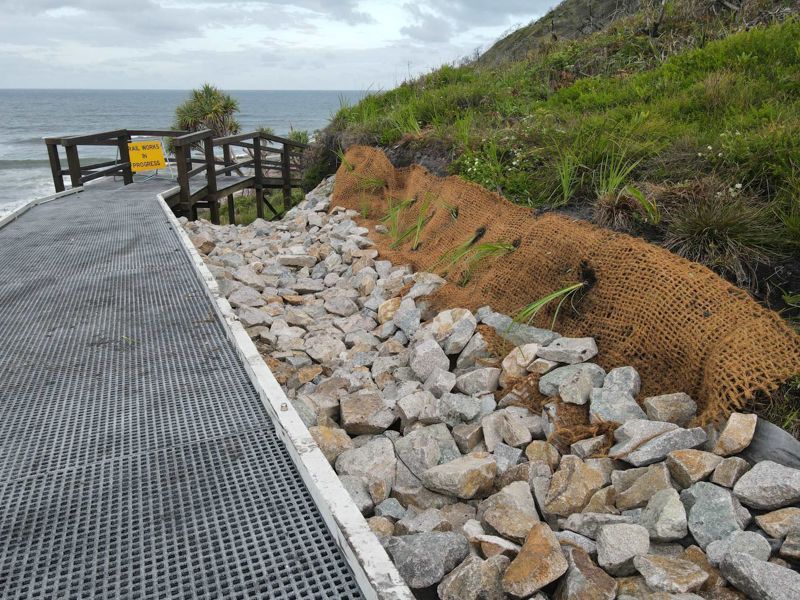 A walkway leading to the ocean with rocks on the side of it.