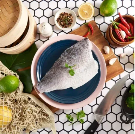 桌子上的盤子裡放著一塊魚，周圍都是蔬菜。