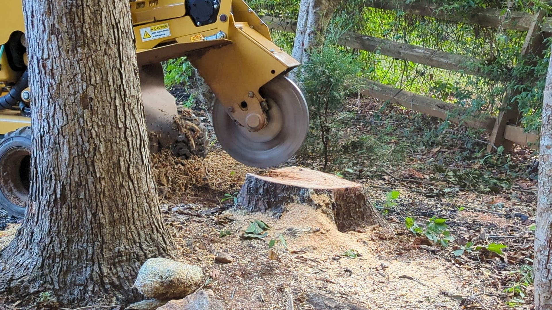 SYS Enterprises team performing stump grinding service on a large tree stump in Charlestown, Indiana, with specialized machinery to clear the area.