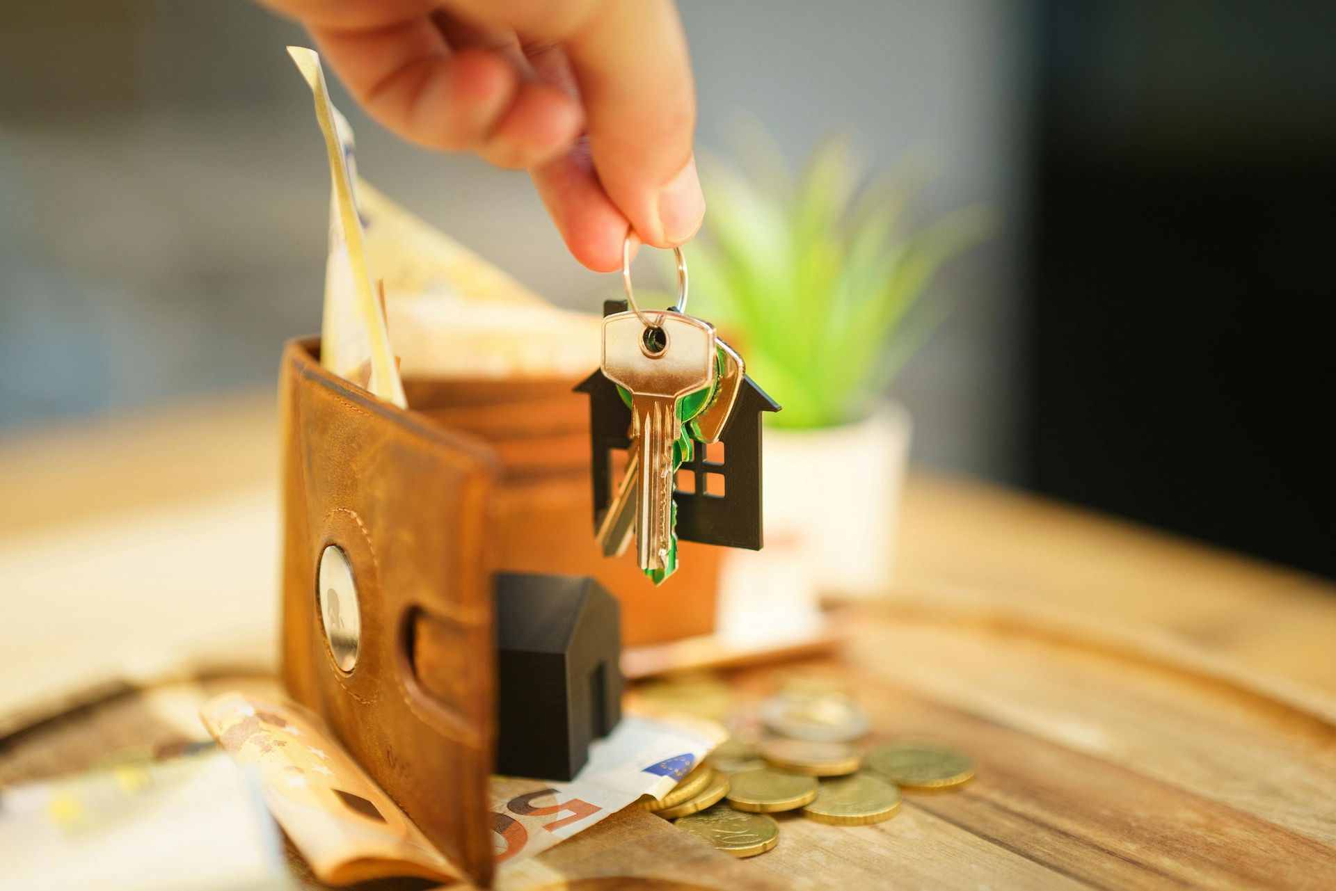 Wallet with cash and house keys featuring a home keychain.