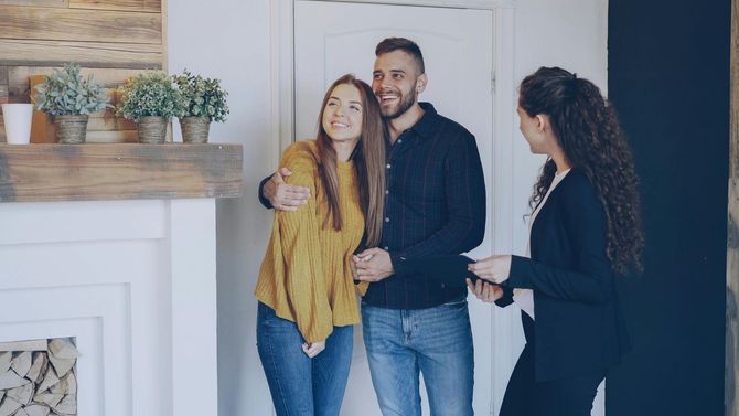 Happy couple receiving keys to their new home from a realtor.