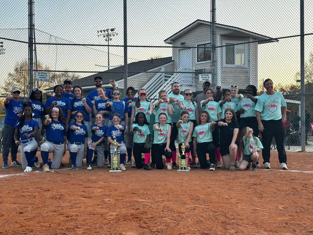 Baseball glove with ball on green grass, with blurred baseballs in the background.