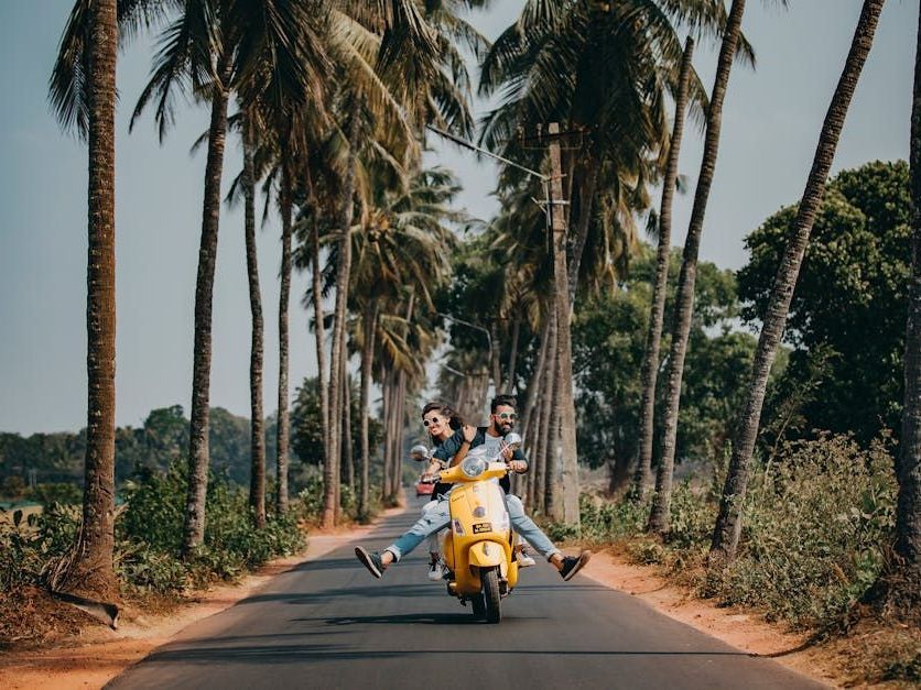 A group of people are riding a yellow scooter down a road.