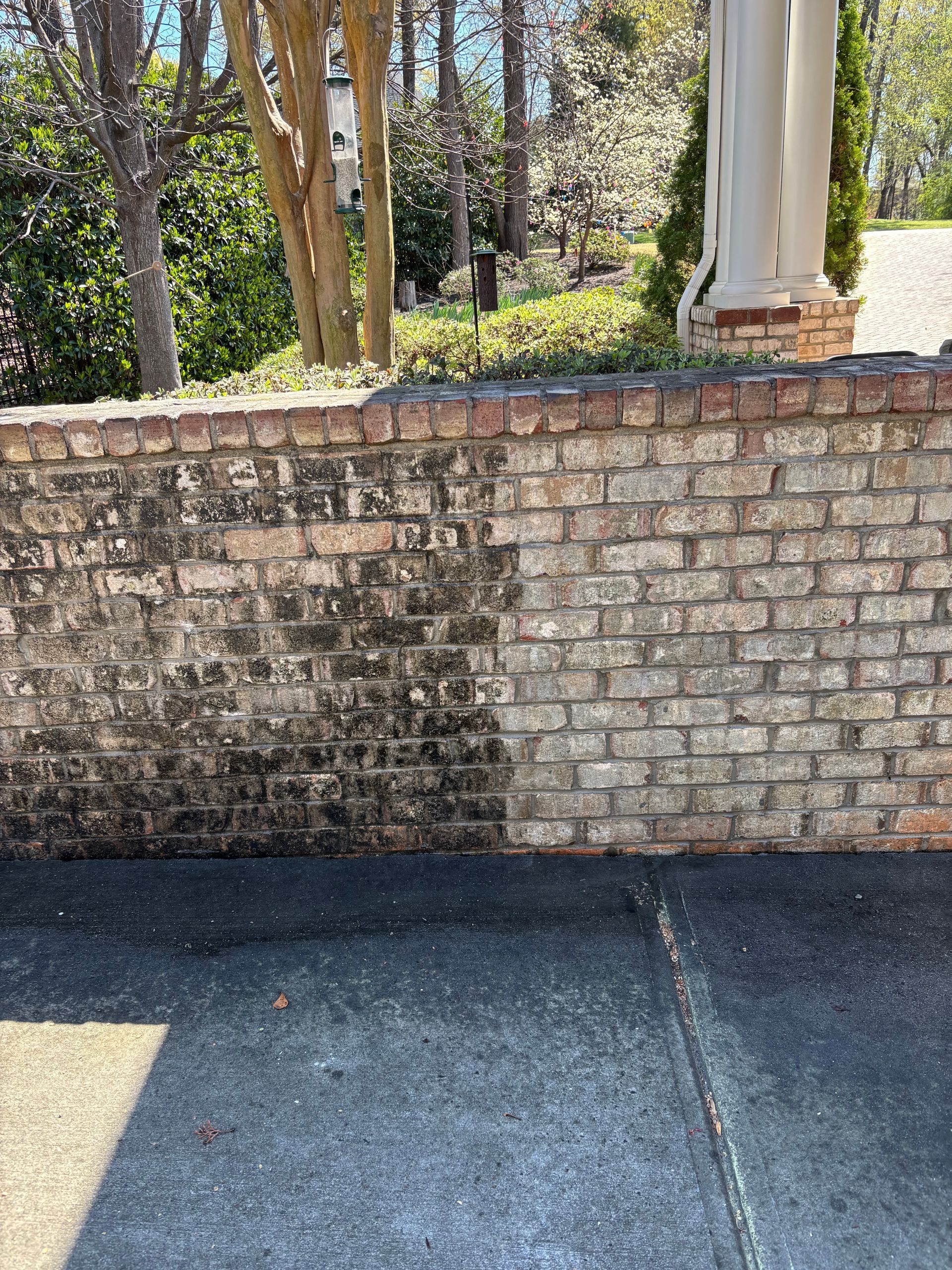 Brick wall, half cleaned and half covered in dark grime, revealing the brick's original color on the right.