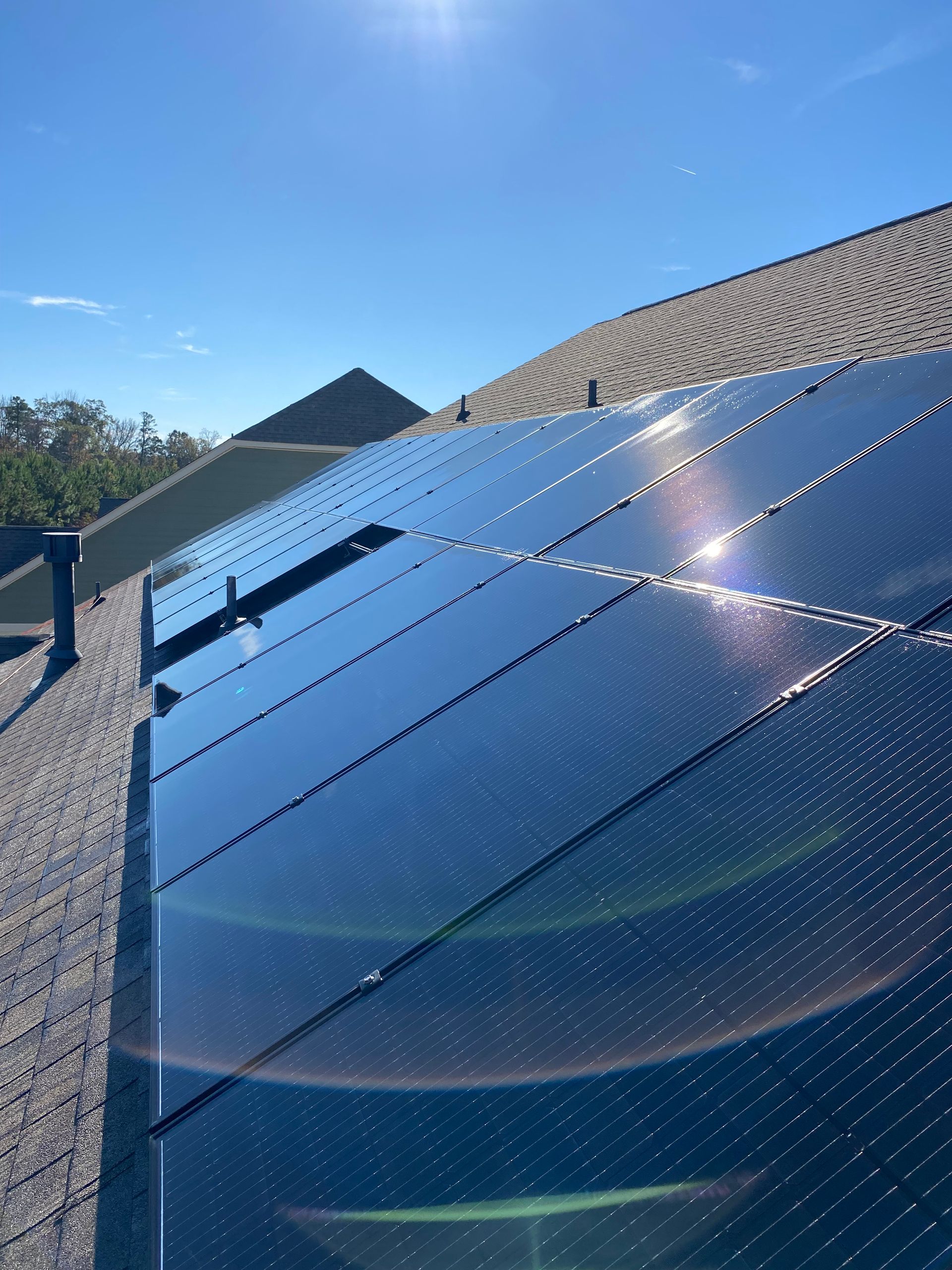 Solar panels on a rooftop against a blue sky, catching the sunlight.