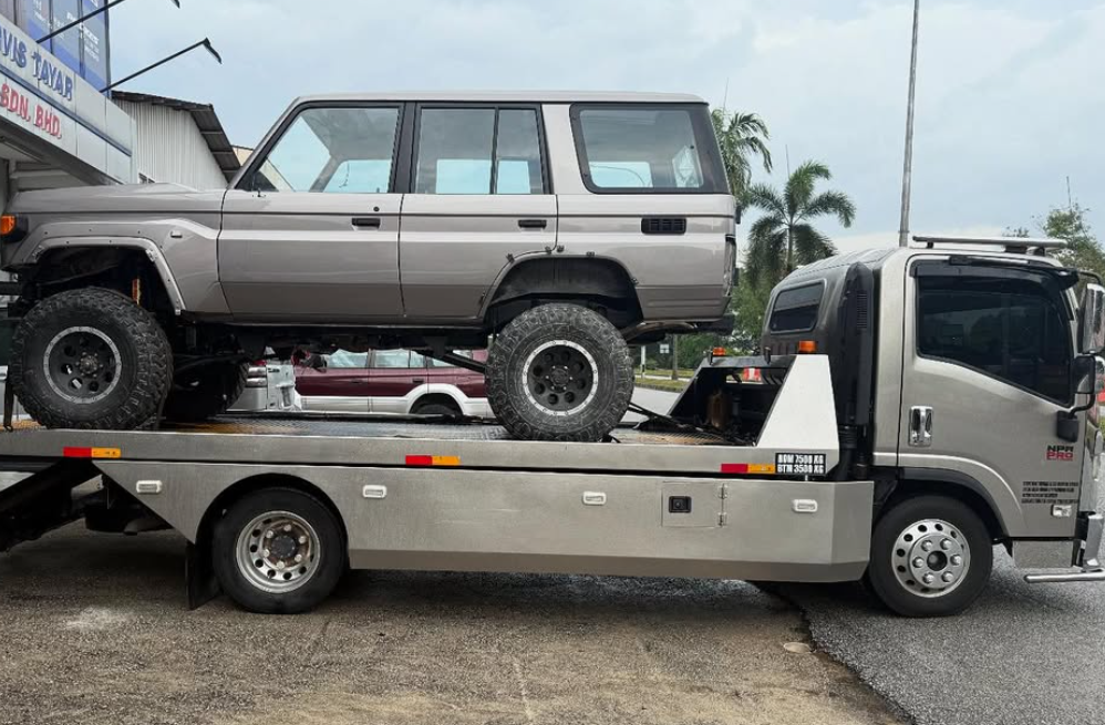 A car is being towed by a tow truck in a parking lot.