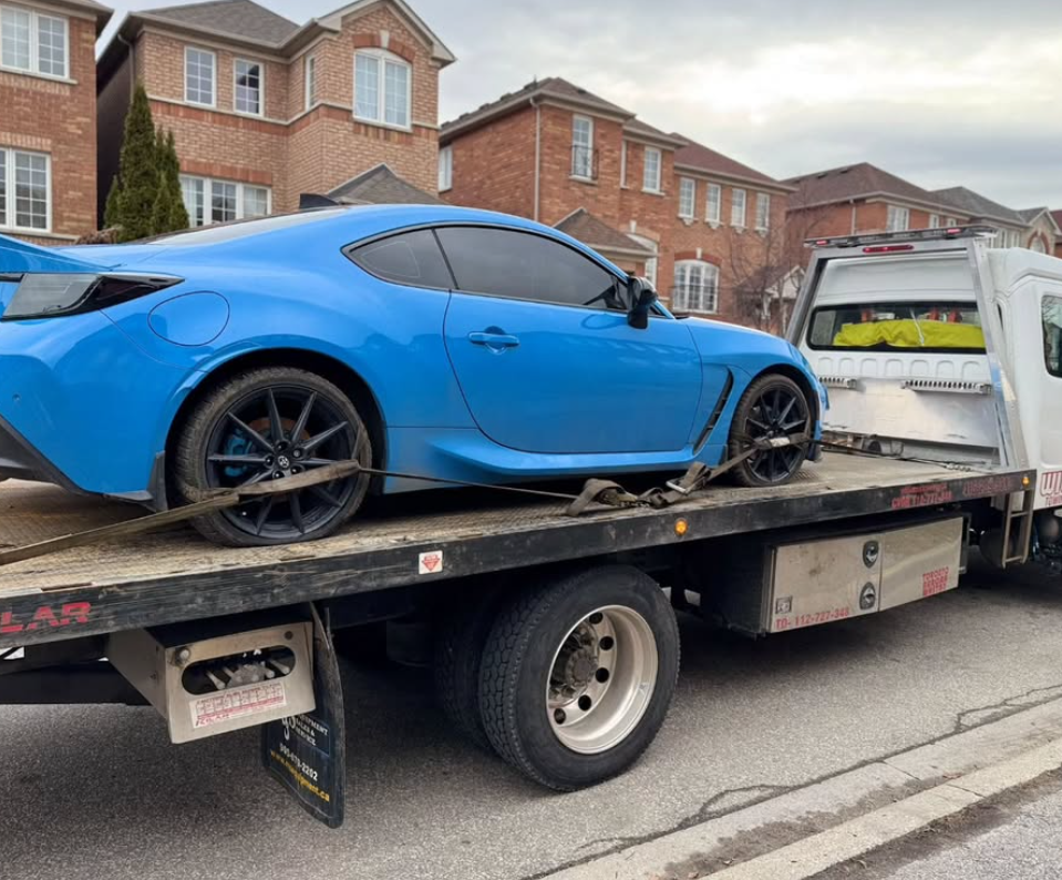 A tow truck with a blue car on the back of it