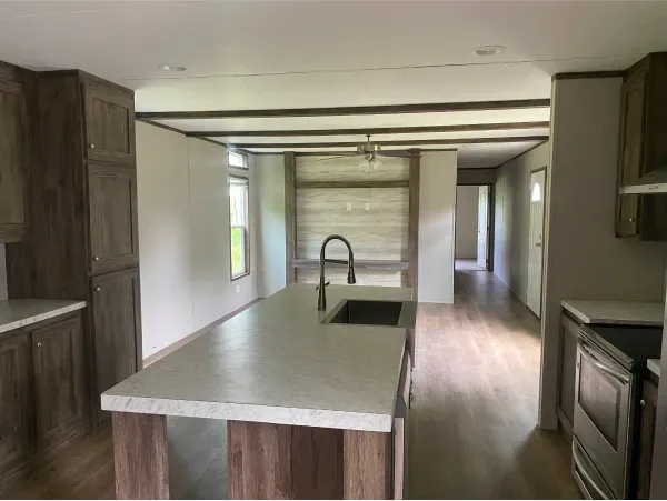 An empty kitchen with a large island and a sink.