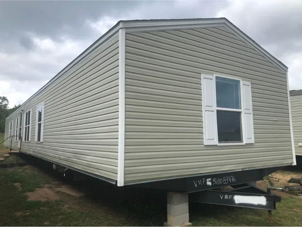 A mobile home is sitting on top of a trailer in a field.