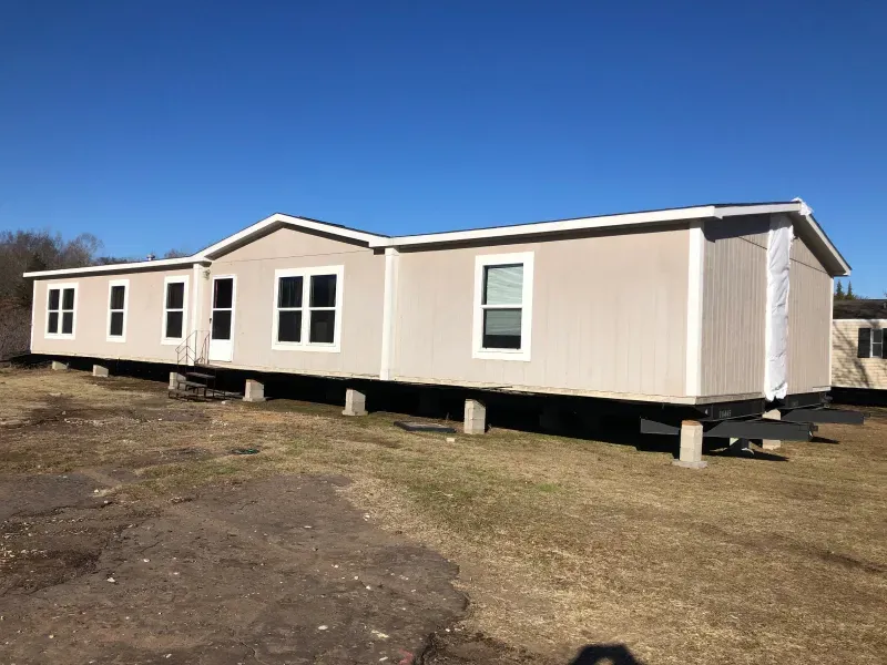 A mobile home is sitting in the middle of a grassy field.