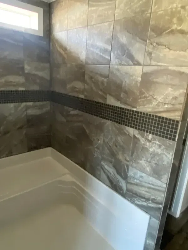 A bathroom with a tub , shower and tiled walls.